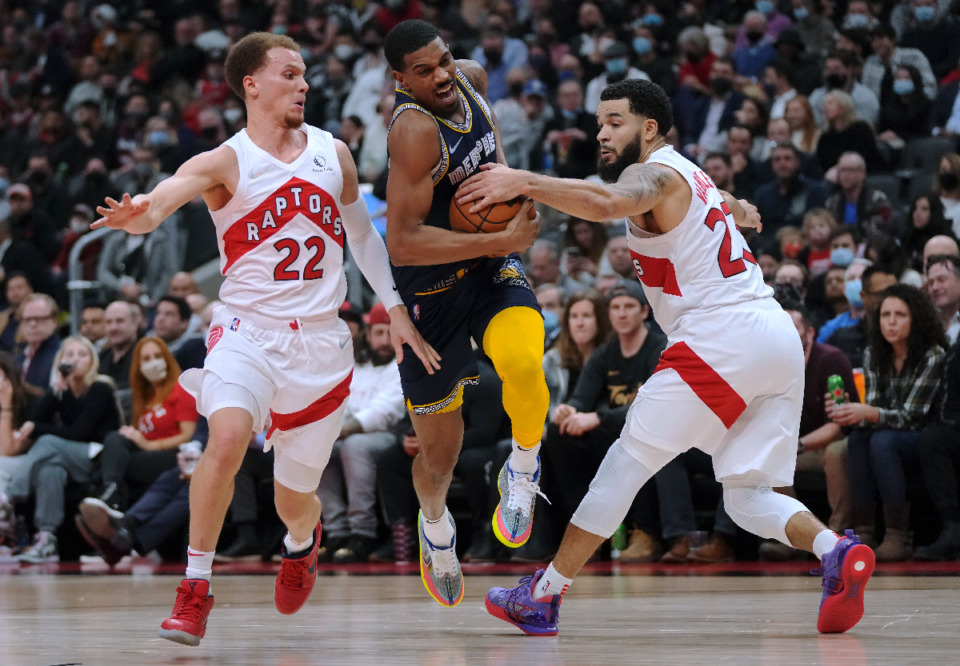 <strong>Memphis Grizzlies guard De'Anthony Melton (0) drives between Toronto Raptors guard Malachi Flynn (22) and guard Fred VanVleet (23) during the first half of an NBA basketball game Tuesday, Nov. 30, 2021, in Toronto.</strong> (Nathan Denette/The Canadian Press via AP)