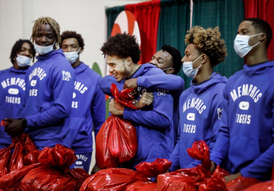 <strong>Memphis players, including Lester Quinones (middle left) and Alex Lomax (middle right), hug and smile while distributing toys during the Tiger Toy Drive on Wednesday, Dec. 15, at the Davis Community Center.</strong> (Mark Weber/Daily Memphian)