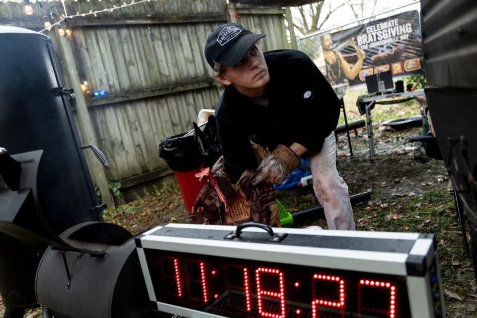 <strong>Addison Fordick adds some charcoal to a vertical offset barrel smoker while attempting to break a Guinness World Record for longest team barbecue.</strong> (Brad Vest/Special to The Daily Memphian)&nbsp;