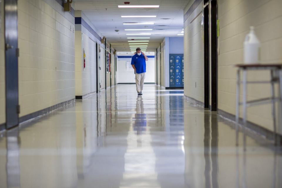 <strong>FILE - A middle school principal walks the empty halls of his school as he speaks with one of his teachers to get an update on her COVID-19 symptoms, Friday, Aug., 20, 2021, in Wrightsville, Georgia. On Monday, Dec. 27, 2021, U.S. health officials cut isolation restrictions for Americans who catch the coronavirus from 10 to five days and also shortened the time that close contacts need to quarantine.</strong> (AP Photo/Stephen B. Morton, File)