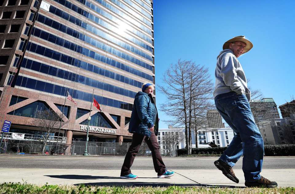 <strong>Carrie (left) and Dave Trimmer look for a trolley on Front Street while walking Downtown on Feb. 24, in front of the Raymond James building in Downtown Memphis.&nbsp; The namesake and anchor for the 21-story building, Raymond James &amp; Associates has plans to move from its office tower to East Memphis&rsquo; Ridgeway Center&nbsp;</strong>(Jim Weber/Daily Memphian)&nbsp;