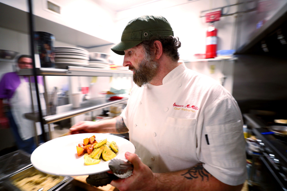 <strong>Caritas Village chef Spencer McMillin hurries through the kitchen, preparing orders as tables quickly fill up for lunch. The nonprofit Binghampton restaurant is known for delicious and affordable farm-to-table meals, which are offered free to anyone in need.</strong> (Houston Cofield/Daily Memphian)