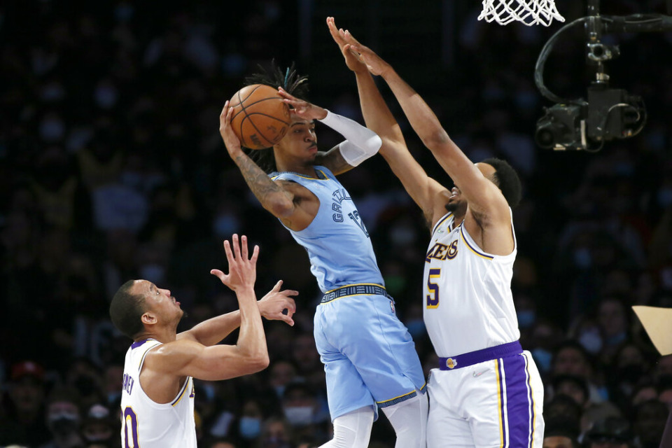 <strong>Memphis Grizzlies guard Ja Morant, center, passes the ball away from pressure by Los Angeles Lakers guard Talen Horton-Tucker, right, and guard Avery Bradley, left, during the second half of an NBA basketball game, Sunday, Jan. 9, 2022, in Los Angeles.</strong> (AP Photo/Alex Gallardo)