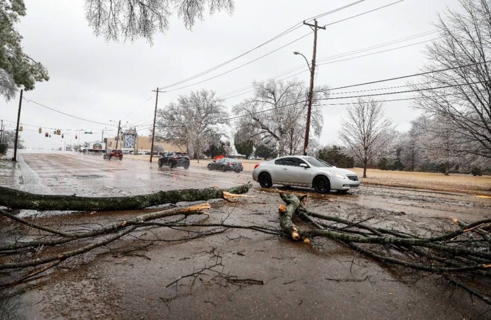 <strong>Cars maneuver around a fallen branch on Poplar Avenue as freezing rain covers trees on Thursday, Feb. 3, 2022.</strong> (Mark Weber/The Daily Memphian)