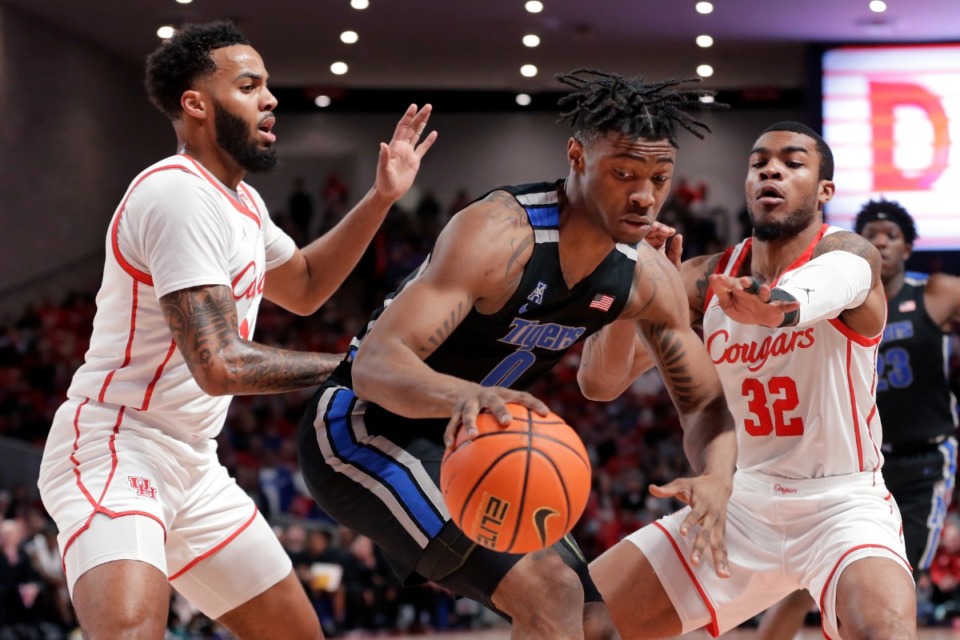 <strong>Memphis guard Earl Timberlake (0) drives between Houston guard Kyler Edwards, left, and Reggie Chaney (32) during the first half of an NCAA college basketball game Saturday, Feb. 12, 2022, in Houston.</strong> (AP Photo/Michael Wyke)