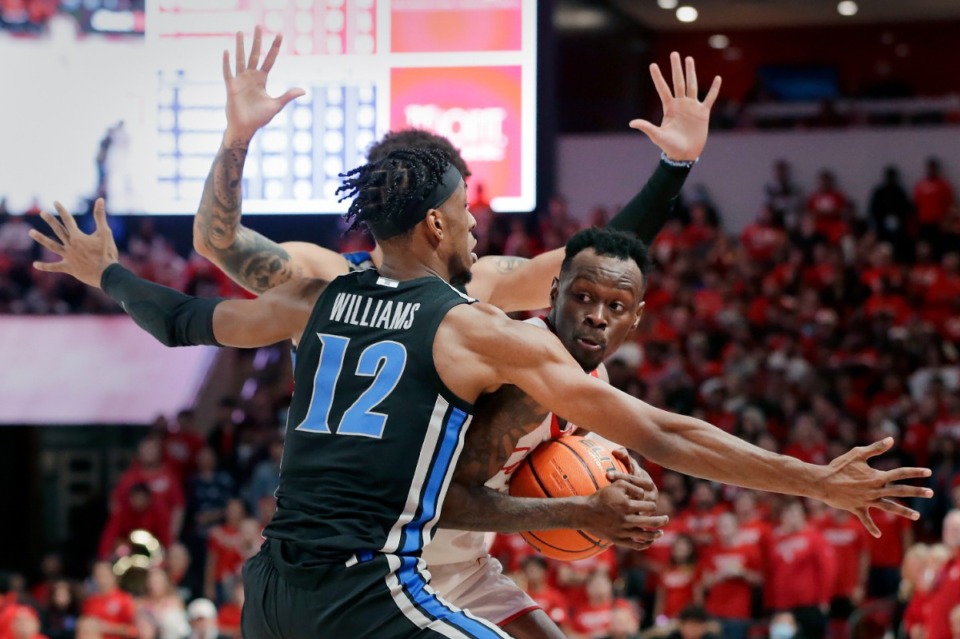 <strong>Houston guard Taze Moore (right), is boxed up by Memphis forward DeAndre Williams (12) and Memphis guard Lester Quinones, (back) during the second half of an NCAA college basketball game Saturday, Feb. 12, 2022, in Houston.</strong> (AP Photo/Michael Wyke)