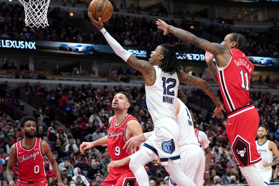 <strong>Memphis Grizzlies' Ja Morant (12) scores past Chicago Bulls' DeMar DeRozan during the second half of an NBA basketball game Saturday, Feb. 26, 2022, in Chicago.</strong> (AP Photo/Charles Rex Arbogast)