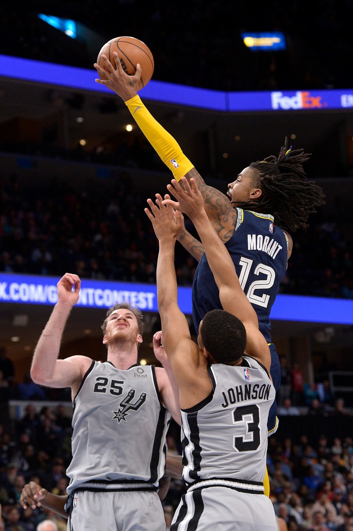 <strong>Memphis Grizzlies guard Ja Morant (12) shoots against San Antonio Spurs center Jakob Poeltl (25) and forward Keldon Johnson (3) on Feb. 28, 2022, at FedExForum.</strong> (Brandon Dill/AP)