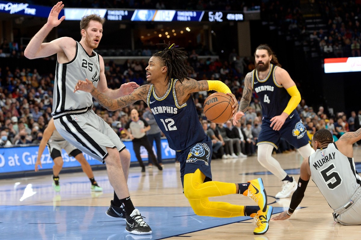 <strong>Memphis Grizzlies guard Ja Morant (12) drives between San Antonio Spurs center Jakob Poeltl (25) and guard Dejounte Murray (5) on Feb. 28, 2022, at FedExForum.</strong> (Brandon Dill/AP)