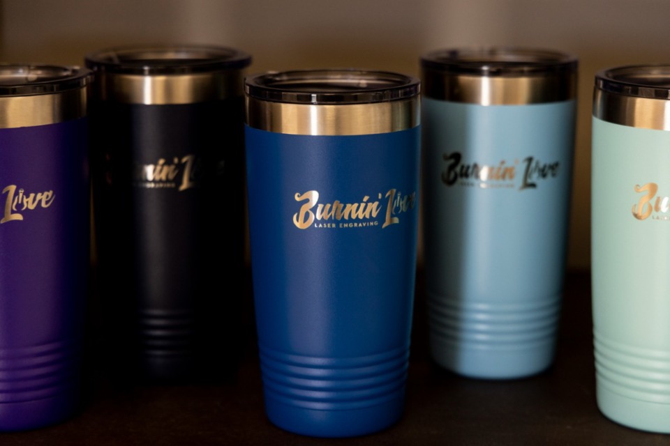 <strong>Colorful travel mugs display the Burnin&rsquo; Love Laser Engraving business logo.</strong> (Brad Vest/Special to The Daily Memphian)