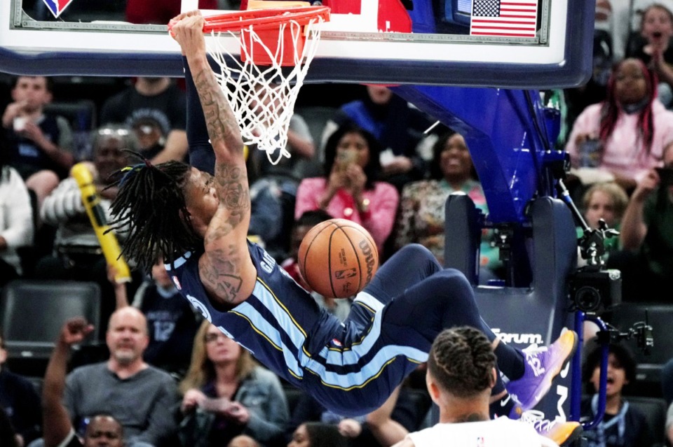 <strong>Ja Morant (12) swings from the rim after a dunk in the second half of an NBA basketball game against the Orlando Magic, Saturday, at FedExForum.</strong> (AP Photo/Karen Pulfer Focht)