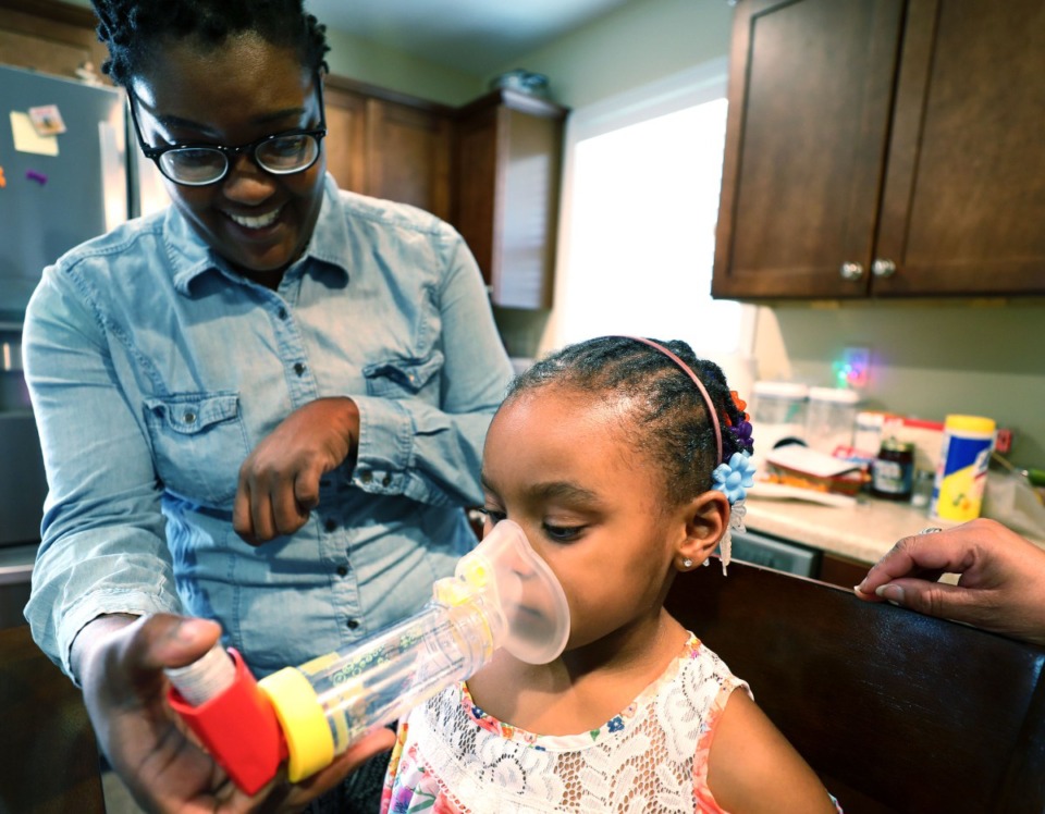 <strong>Marlisa Harris (left) assists her daughter Marlie Harris, 5, as she uses her asthma inhaler to treat chronic asthma. </strong>(Houston Cofield/Daily Memphian file)