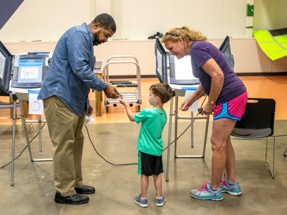 <strong>Poll worker Chris Evans hands Dominic Pitcock, 4, an "I Voted" sticker after he helped his grandmother, Cheryl Brogdon, vote at Hope Church on Tuesday, May 3, 2022.</strong> (Greg Campbell/Special to The Daily Memphian)