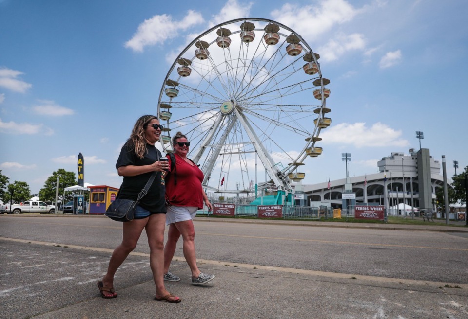 <strong>Briana Macias (left) and Teri Daniels walk past the Ferris wheel at the 2022 World Championship Barbecue Cooking Contest at Liberty Park in Memphis on Wednesday, May 11.</strong> (Patrick Lantrip/Daily Memphian)