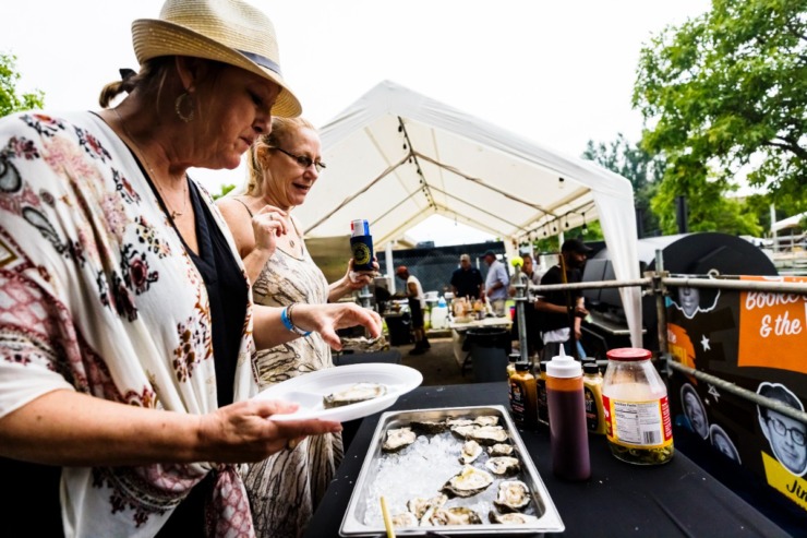<strong>Dawn Dennis (left) and Allison Handwerker sample oysters at Tin Top BBQ tent.</strong> (Ziggy Mack/Special to The Daily Memphian.)