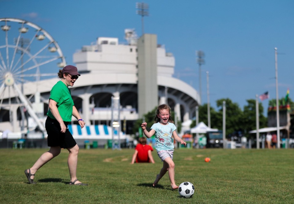 <strong>Pauline LeBlond of the Planet BBQ tent plays soccer with her daughter, Charlotte, during the last day of the Memphis in May World Championship Barbecue Cooking Contest at Liberty Park.</strong> (Patrick Lantrip/Daily Memphian)