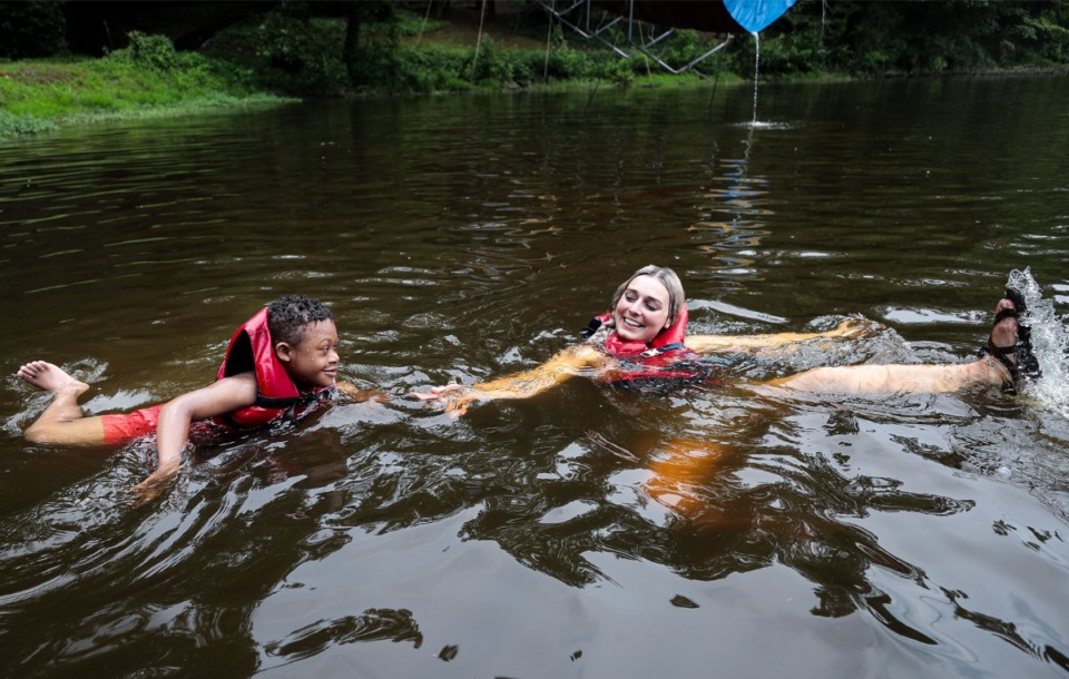 <strong>A counselor at Camp Able helps a camper swimming in the lake at St. Columba in Bartlett June 7, 2022.</strong> (Patrick Lantrip/The Daily Memphian)