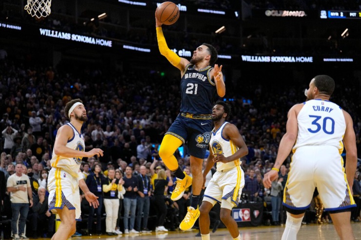 Memphis Grizzlies guard Tyus Jones (21) drives to the basket against Golden State' Klay Thompson, left, Andrew Wiggins (22) and Stephen Curry (30) during the second half of Game 4 of an NBA basketball Western Conference playoff semifinal in San Francisco, Monday, May 9, 2022. (AP Photo/Tony Avelar)