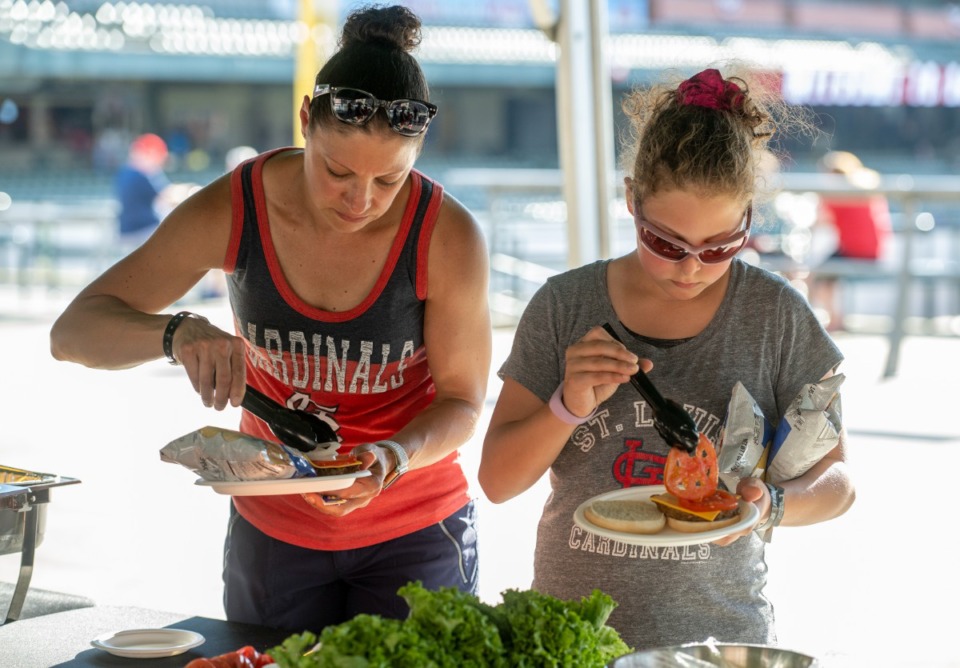 <strong>Jamie Goldstein (left) and daughter Charlie Goldstein load up on their all you can eat hamburgers and hot dogs at the Fourth of July celebration at the Redbirds game at AutoZone Park, Friday, July 1, 2022.</strong> (Greg Campbell/Special for The Daily Memphian)