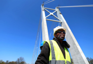 <strong>Alvin Griggs, a general contractor for Flintco., cleans up a job site with co-workers on top of the new pedestrian bridge over Southern Ave. on the University of Memphis campus. The $33 million project which includes a bridge, parking garage, walking paths, and an outdoor amphitheatre is set to be finished for the 2019 fall semester.</strong> (Houston Cofield/Daily Memphian)