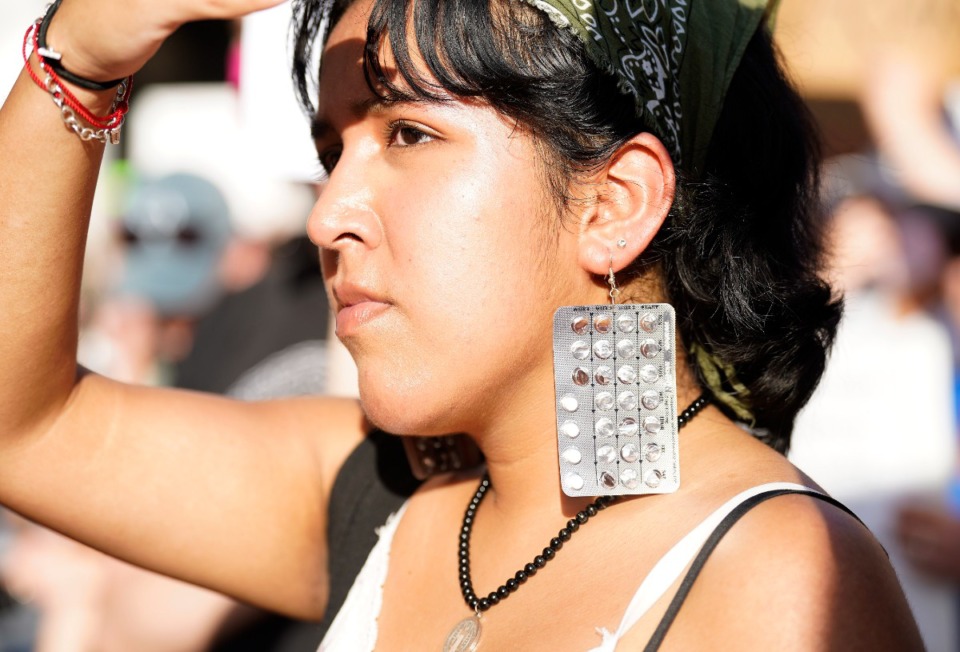 <strong>A woman wears earrings made out of birth control pills during a protest against the Supreme Court's decision to reverse Roe v. Wade.</strong> (Karen Warren/AP)
