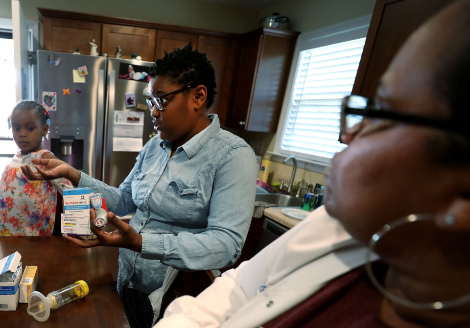 <strong>Marlisa Harris (center) explains how the medication she has received to treat her daughter Marlie's asthma works. Harris's daughter Marlie Harris (left), 5, has benefited from LeBonheur's Changing High-Risk Asthma in Memphis through Partnership (CHAMP) program, and says her daughter has seen improved energy throughout the day.</strong> (Houston Cofield/Daily Memphian)