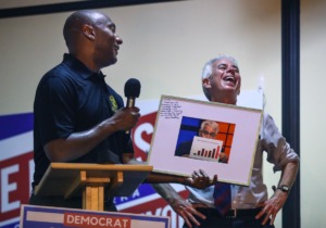 <strong>Shelby County Mayor Lee Harris hands Steve Mulroy a picture of himself holding a sign on the &ldquo;Behind the Headlines&rdquo; podcast at a joint victory party for the Democratic candidates on Thursday, Aug. 4. Mulroy defeated incumbent Amy Weirich in the contest for district attorney.</strong> (Patrick Lantrip/Daily Memphian)