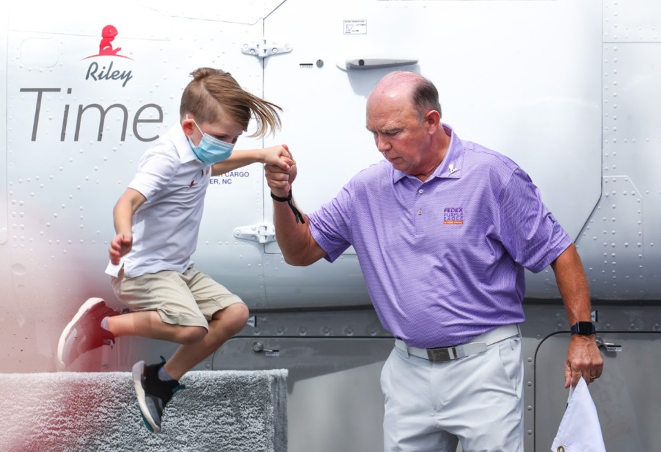 <strong>Bill West helps Riley, a St. Jude patient, down off of a riser after having a FedEx Cessna Caravan named in his honor at the FedEx St. Jude Championship Aug. 10, 2022.</strong> (Patrick Lantrip/Daily Memphian)