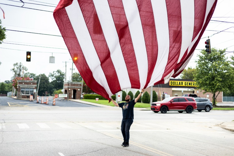 <strong>Justin Clements helps raise a flag as the event started at Tiger Lane.</strong> (Brad Vest/Special to The Daily Memphian)