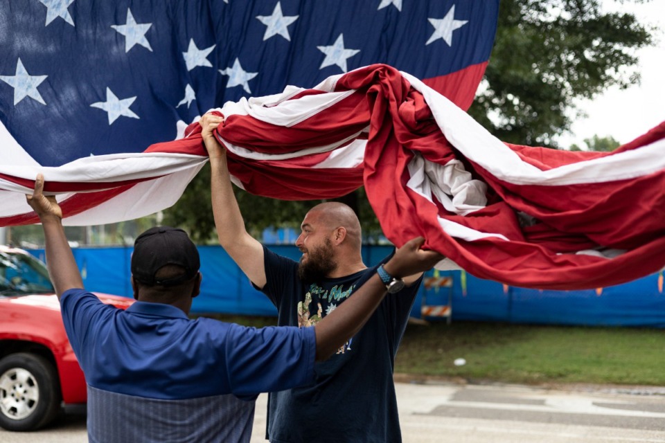 <strong>Justin Clements (right) and Frederick McCullough help raise a flag before the start of the Sea of Red event.</strong> (Brad Vest/Special to The Daily Memphian)