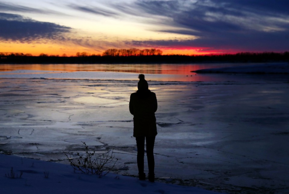 <strong>Bridget McCall watches the sunset over an icy Mississippi River in Memphis, Feb. 19, 2021. A 10-day cold front brought record snowfall and freezing temperatures to the region.</strong> (Patrick Lantrip/The Daily Memphian)