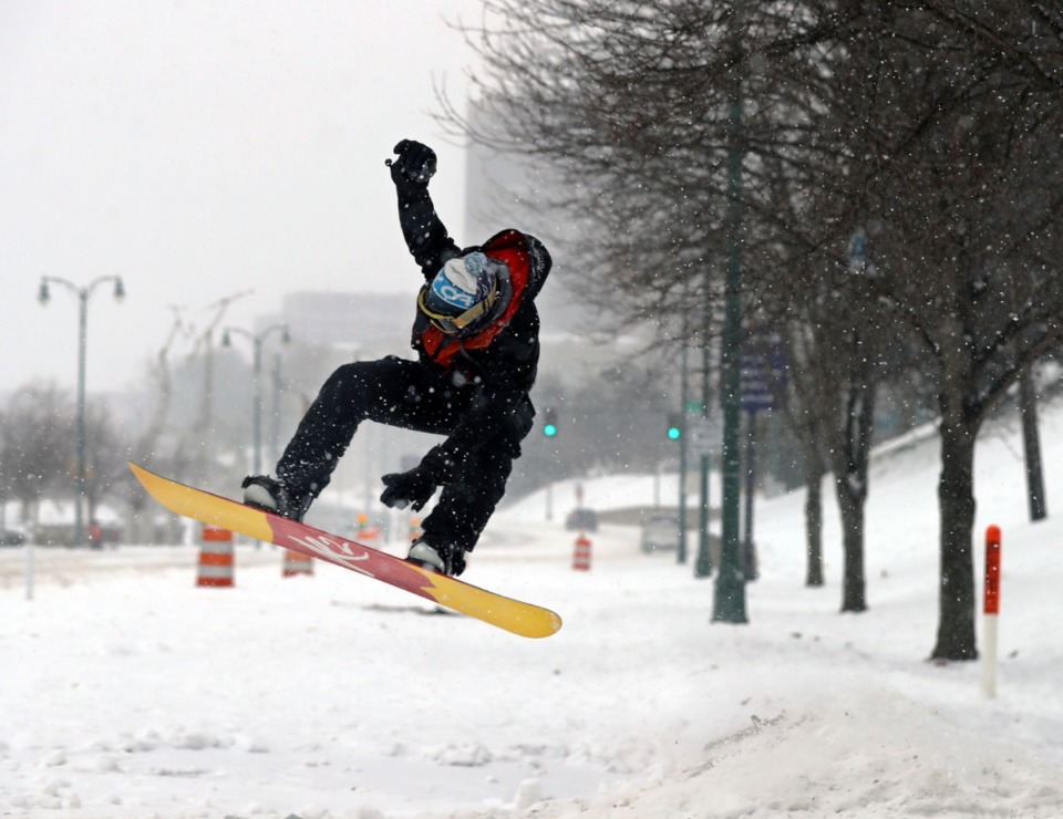 <strong>Beau Bowden grabs his snowboard while catching air at the bottom of the Mississippi River Bluffs in Downtown Memphis, Feb. 17, 2021. Record snowfall turned the normally mild Memphis winter into an alpine-sports haven.</strong> (Patrick Lantrip/The Daily Memphian)
