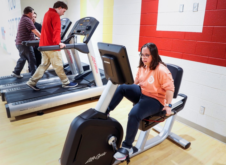 <strong>Rachel Krug demonstrates a new exercise bike inside the recently completed fitness center at Madonna Learning Center on Oct. 26, 2022.</strong> (Mark Weber/The Daily Memphian)