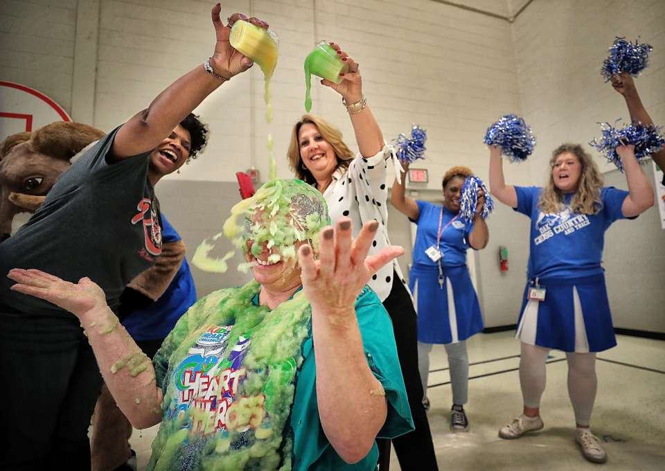 <strong>Tamrelyn Banning gets doused in green apple sauce by vice principal Cam Alexander (left) and principal Stephanie Beech during an assembly at Oak Elementary in Bartlett on April, 12, 2019, to celebrate the school meeting their heart-healthy goal of getting exercise and choosing milk or water over sugary drinks. As a reward they got to slime their gym teacher. </strong>(Jim Weber/Daily Memphian)