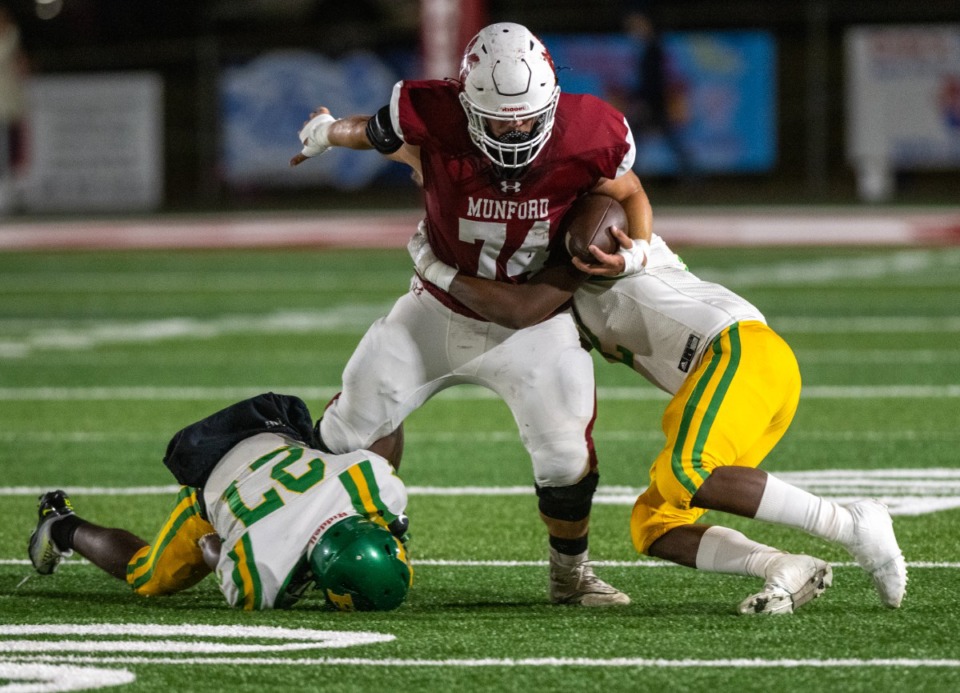 <strong>Munford High School's Zach Smith is dragged down by Central High School defenders on Oct. 28. Both teams will be Region 8-5A.</strong> (Greg Campbell/The Daily Memphian file)