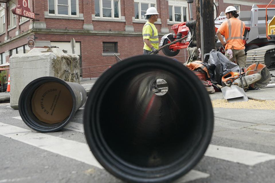 <strong>Workers stand next to new water main pipes at the site of a project in downtown Tacoma, Wash.&nbsp;last June. Like Memphis,&nbsp;much of the nation is struggling to catch up to aging systems.</strong> (Ted S. Warren/AP Photo)