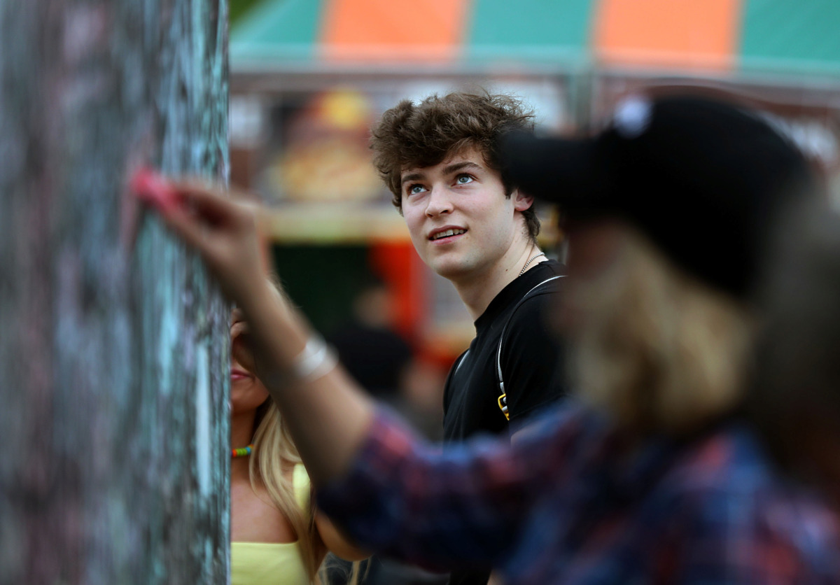 <strong>Nick Mortoza eyes a wall full of chalk signatures at the Beale Street Music Festival on Friday, May 3, 2019, in Tom Lee Park. The communal art wall was provided by the Downtown Memphis Commission.</strong> (Patrick Lantrip/Daily Memphian)
